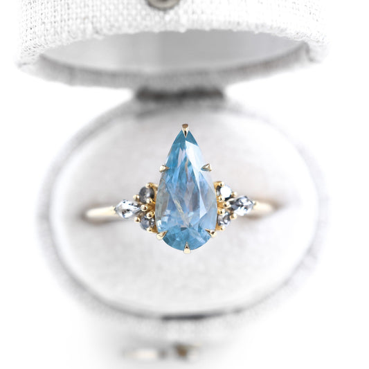 Pear shaped blue gemstone ring with diamond sidestones set in gold