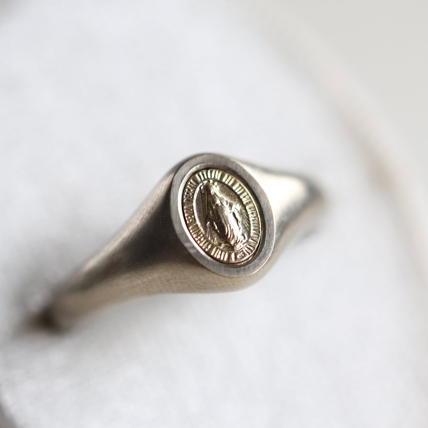 Krupni plan prstena sa pečatom Device Marije od platine, minimalistički dizajn, dostupne opcije od 14K ili 18K zlata, Meri Mere 7k5mm.