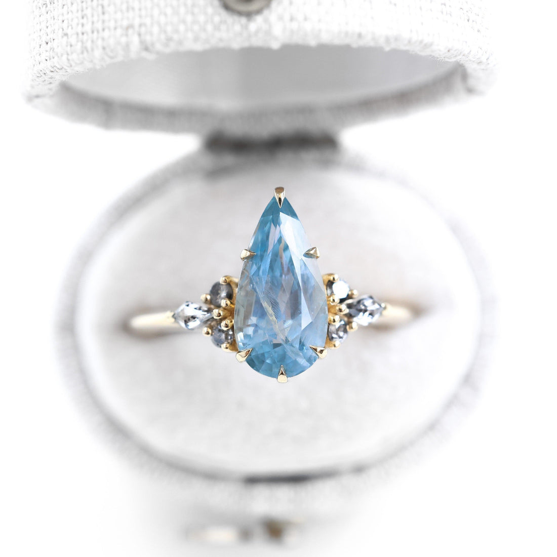 Pear shaped blue gemstone ring with diamond sidestones set in gold