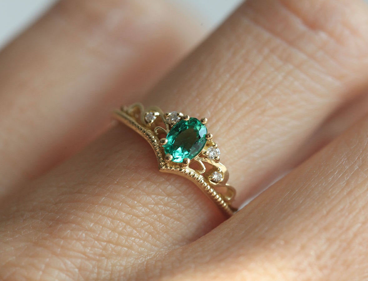 Elegantan ovalni smaragdni prsten sa smaragdnim klasterom markiznog reza i dijamantima. Bend u vintage stilu od 14k ili 18k zlata.