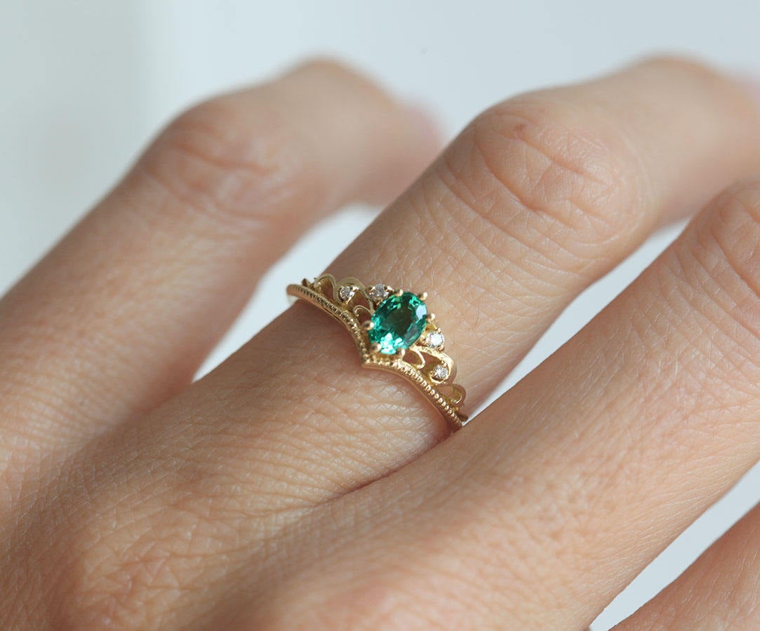 Elegantan ovalni smaragdni prsten sa smaragdnim klasterom markiznog reza i dijamantima. Bend u vintage stilu od 14k ili 18k zlata.
