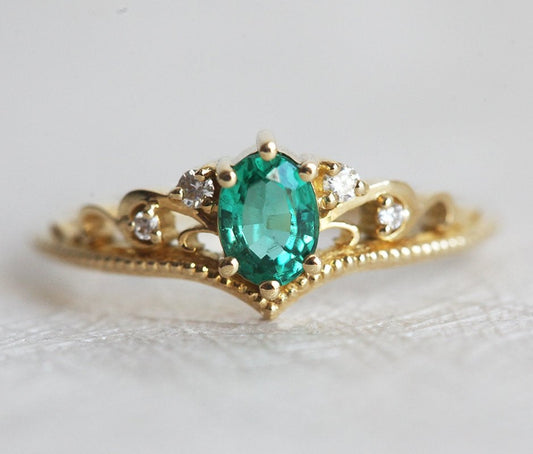 Elegantan ovalni smaragdni prsten sa smaragdnim klasterom markiznog reza i dijamantima. Bend u vintage stilu od 14k ili 18k zlata.