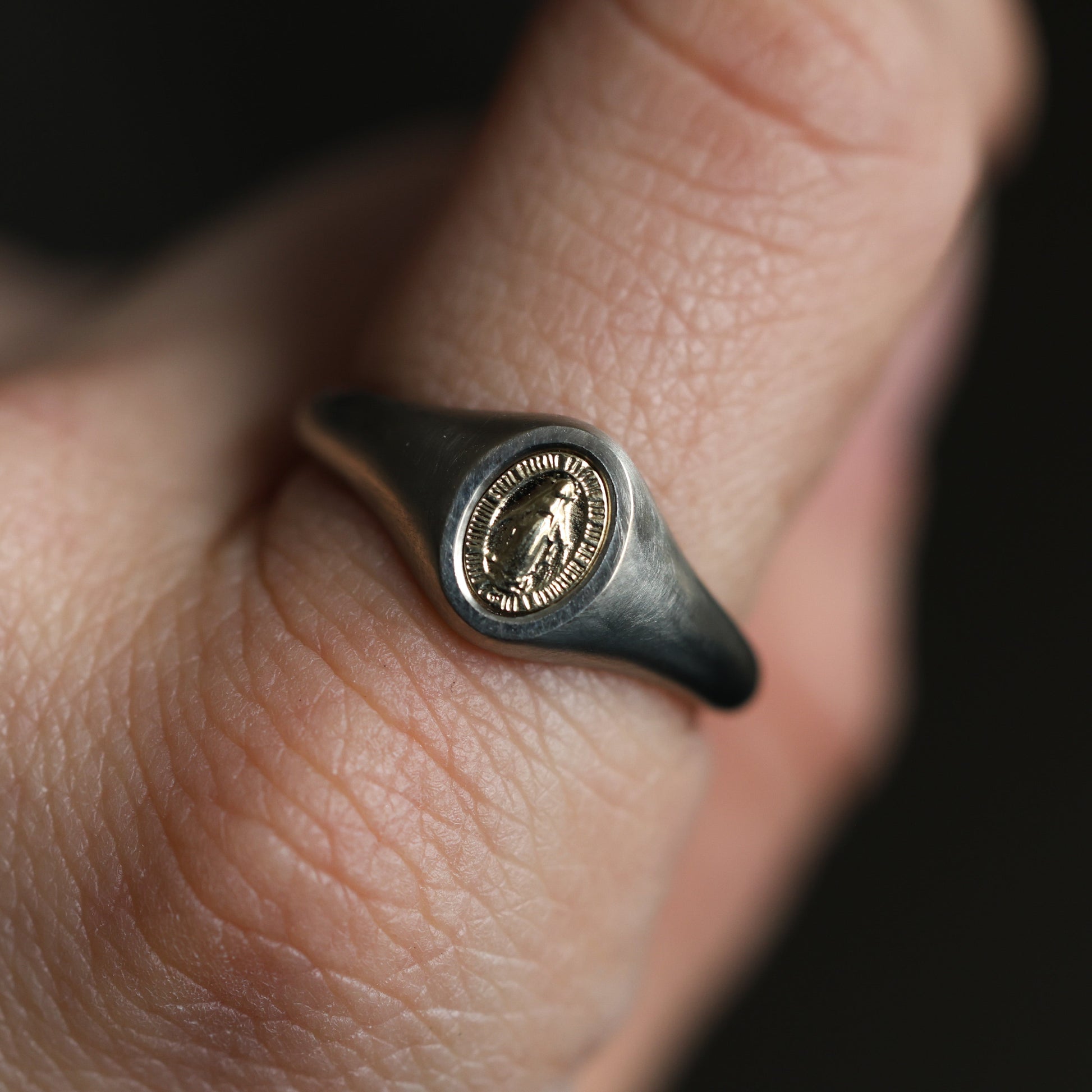 Krupni plan minimalističkog prstena sa pečatom Device Marije od 14K ili 18K zlata.