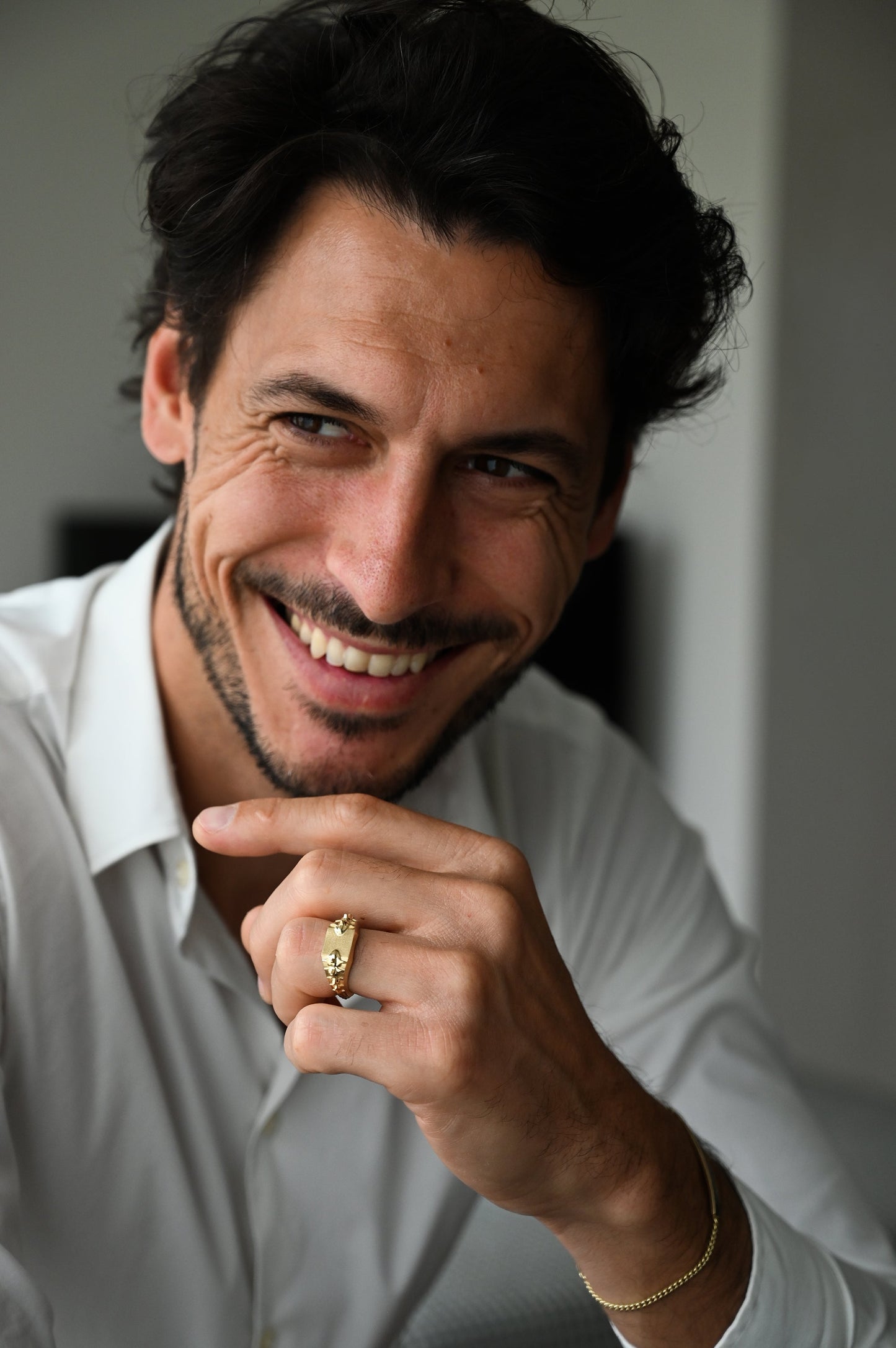 Nasmejani muškarac nosi zlatni prsten sa pečatom sa detaljima kičme zmije.