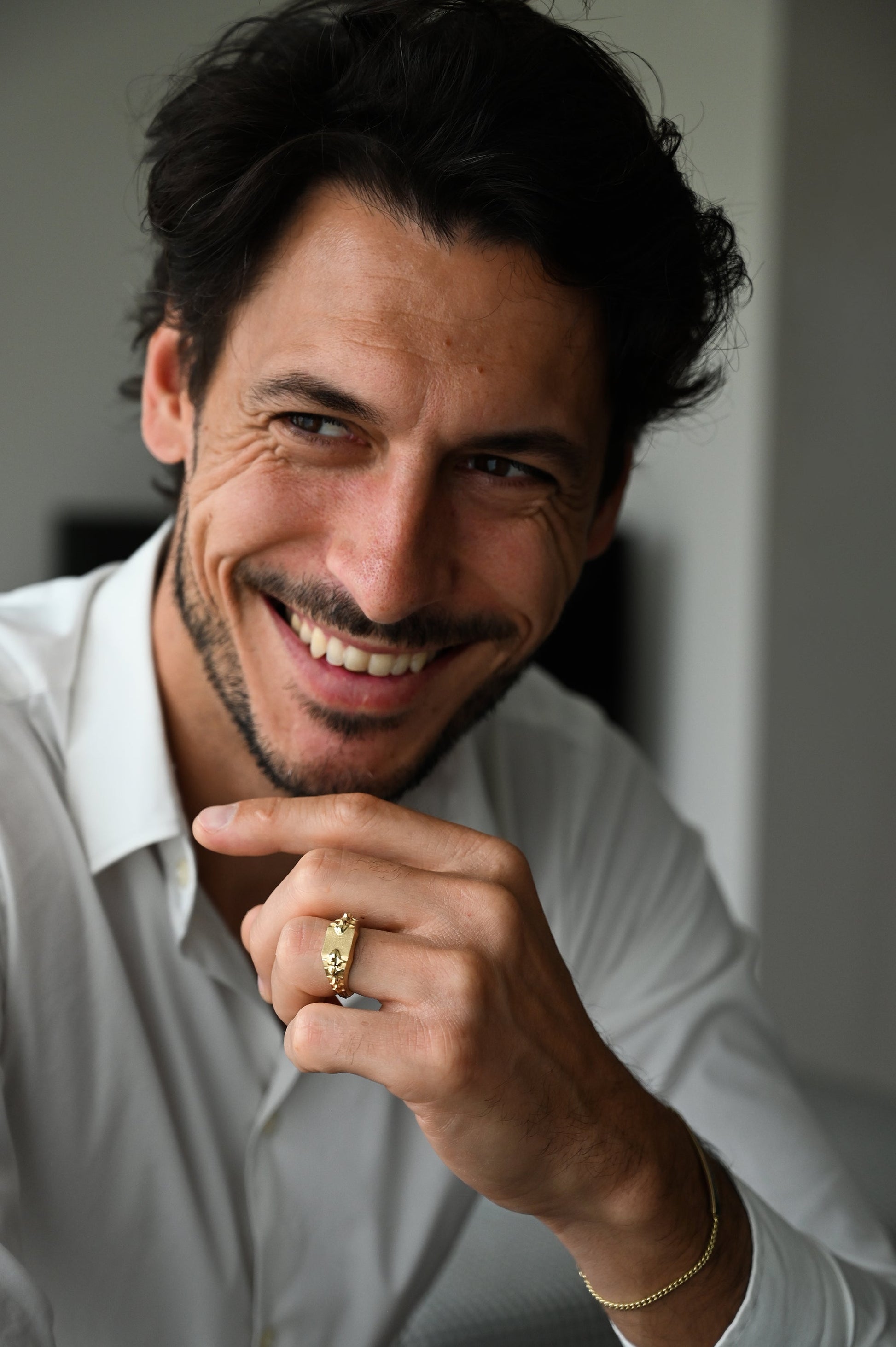 Nasmejani muškarac nosi zlatni prsten sa pečatom sa detaljima kičme zmije.